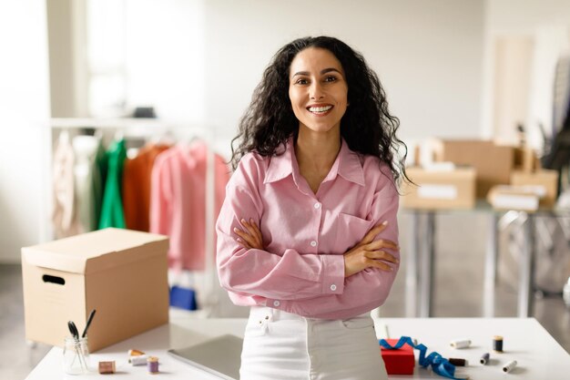 Foto exitosa mujer diseñadora de ropa posando de pie en la sala de exposición