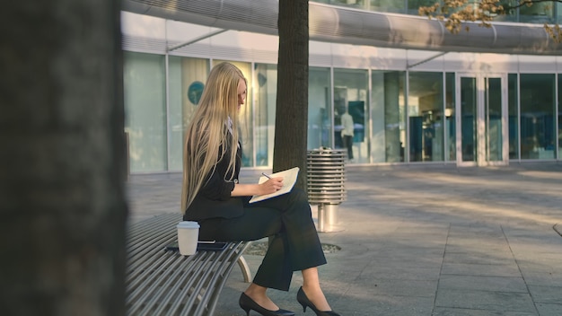 Exitosa mujer joven tomando notas al aire libre.