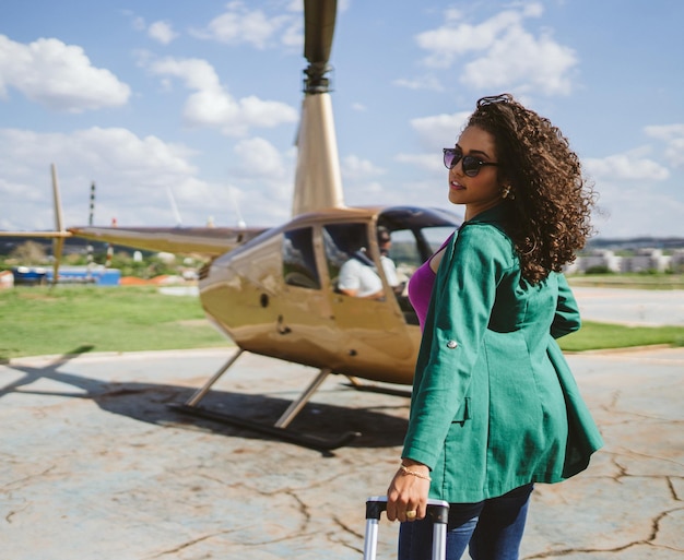 Exitosa mujer latina joven inteligente y elegante cerca del helicóptero. Concepto de estilo de vida de lujo