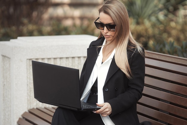 Exitosa mujer de negocios de 35 a 40 años que trabaja en línea, escribe en el teclado de una computadora portátil y trabaja