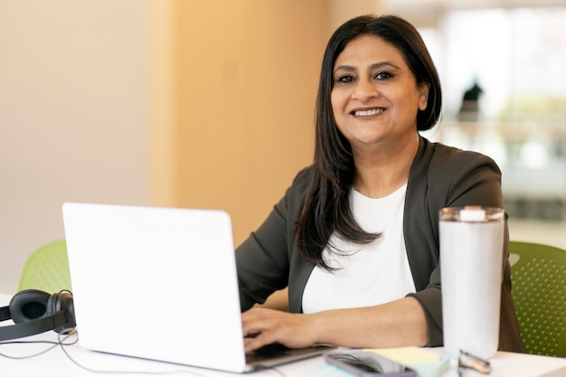 Exitosa mujer de negocios asiática madura que usa laptop trabaja en línea sonríe mirando la cámara