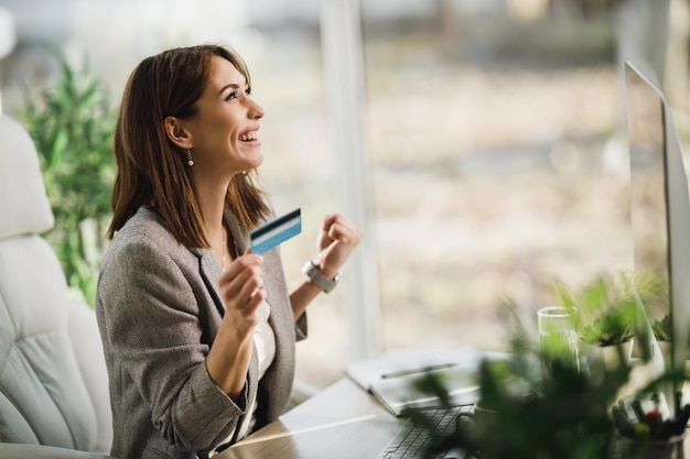 Una exitosa mujer de negocios joven que compra en línea mientras trabaja en su computadora en la oficina.