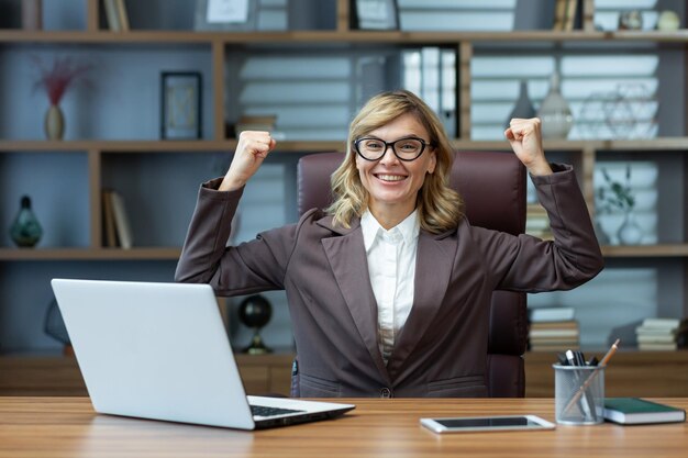 Exitosa mujer de negocios madura levantando las manos gesto de confianza y fuerza sonriendo y