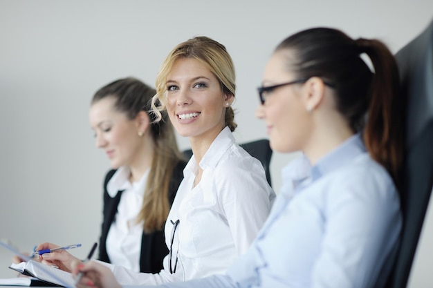 Exitosa mujer de negocios de pie con su personal en segundo plano en una oficina moderna y luminosa