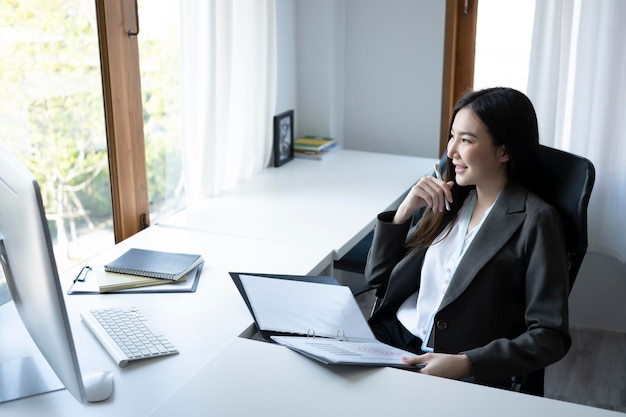 Exitosa mujer de negocios sentada en su lugar de trabajo y mirando por la ventana.