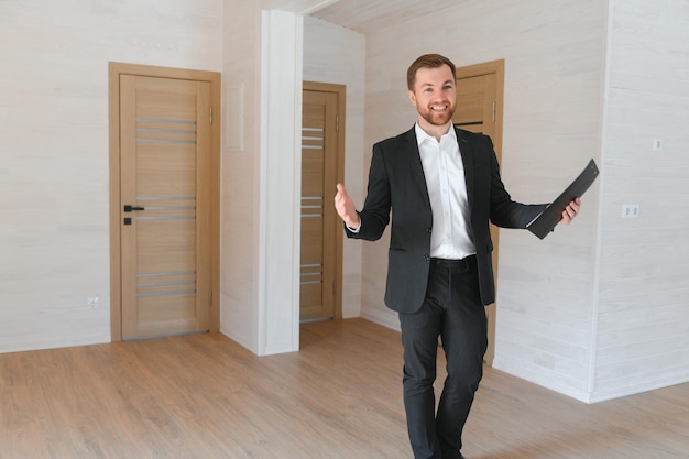 Foto un exitoso agente inmobiliario se encuentra en un nuevo edificio modular y ofrece un nuevo hogar