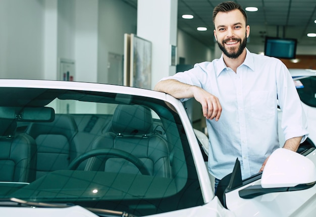 Foto exitoso apuesto hombre barbudo comprando un nuevo auto deportivo en el concesionario