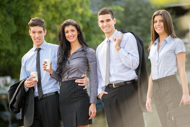 Exitoso equipo de negocios joven durante un descanso para tomar café, caminando en un parque y disfrutando de un día soleado.