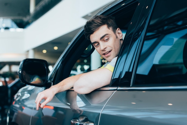 Foto exitoso hombre feliz sonriendo mientras está sentado en un automóvil