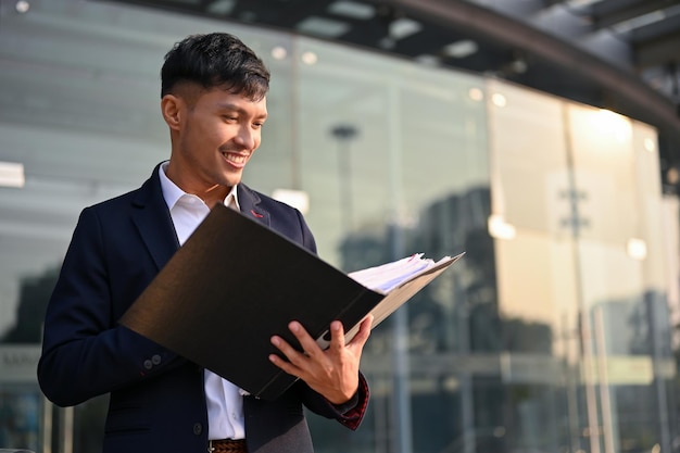 Exitoso hombre de negocios asiático revisando su documento comercial en el archivo del documento