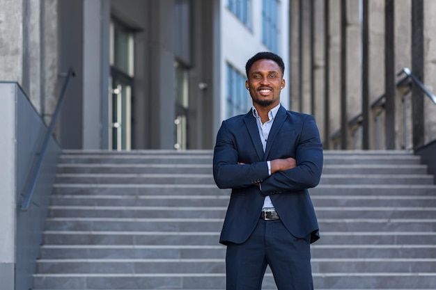 Exitoso hombre de negocios feliz fuera de la oficina posando y mirando a la cámara hombre afroamericano en traje de negocios sonriendo