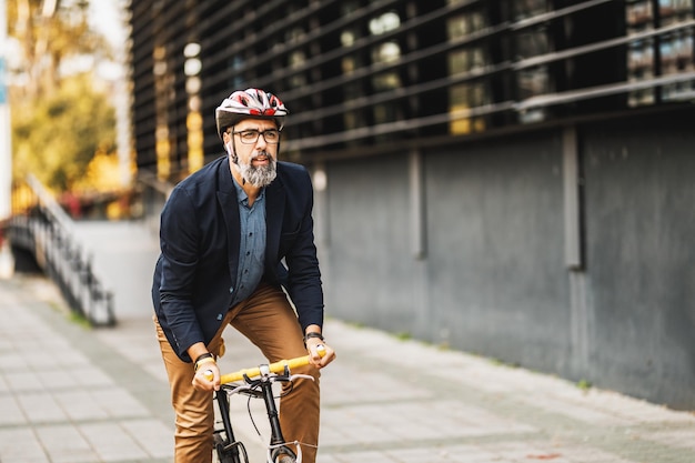 Exitoso hombre de negocios de mediana edad montando en bicicleta camino al trabajo por la ciudad.