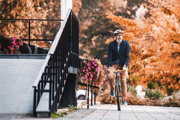 Exitoso hombre de negocios de mediana edad montando en bicicleta camino al trabajo por la ciudad.