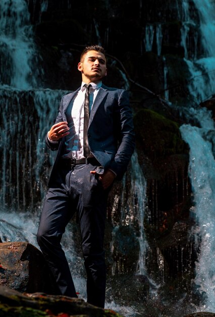 Exitoso hombre de negocios moderno carrera superior hombre de negocios guapo en traje en el fondo de la cascada