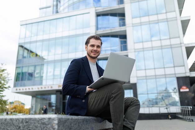 Exitoso hombre de negocios trabaja remotamente en línea al aire libre en el contexto de una ciudad
