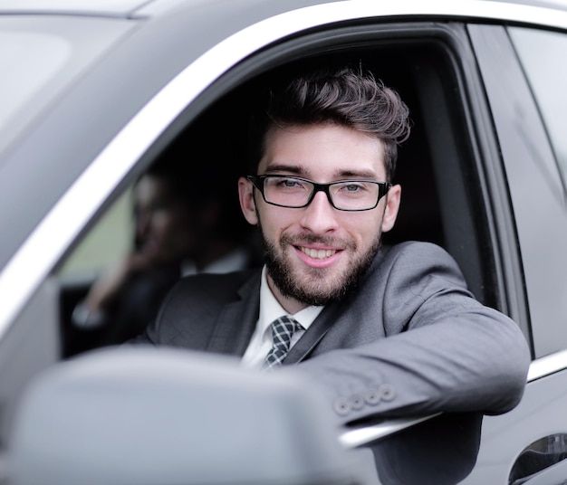 Exitoso hombre de negocios en traje conduciendo su lujoso auto