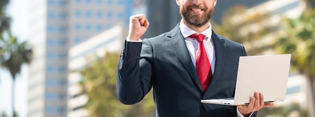 Exitoso hombre de negocios en traje de pie al aire libre con redes portátiles