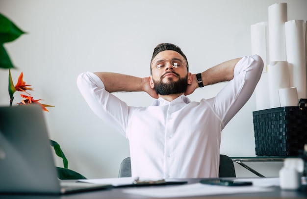 El exitoso hombre de oficina de barba moderna tiene un descanso después de un trabajo duro y bueno en su escritorio de trabajo