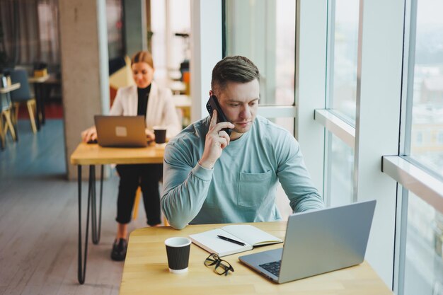 Exitoso líder de negocios pensando en futuras ideas de planes de éxito corporativo sentado en el escritorio de la oficina con una computadora portátil mirando la ventana panorámica del edificio de la corporación moderna