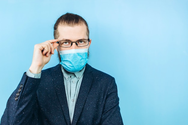 Un exitoso muschin en un traje, gafas y una máscara médica en azul