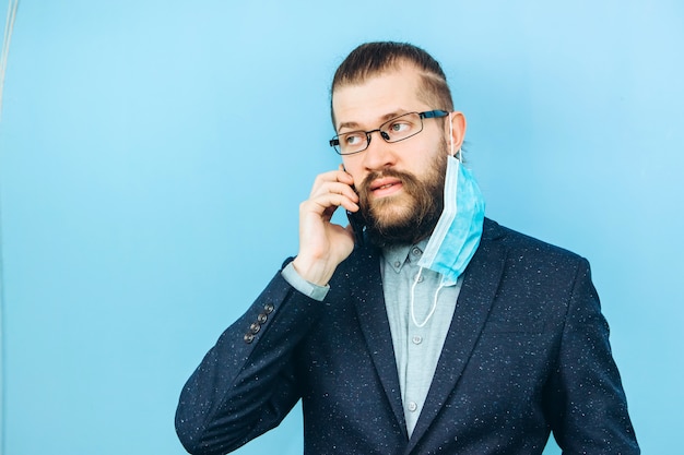 Un exitoso muschin en un traje, gafas y una máscara médica en azul