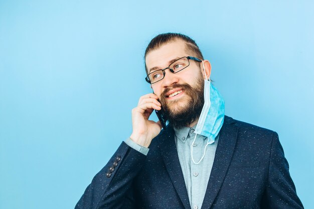 Un exitoso muschin en un traje, gafas y una máscara médica en azul