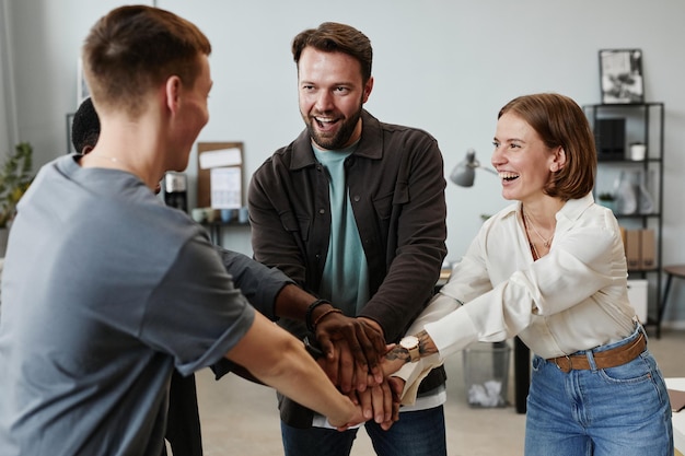 Exitosos empresarios tomándose de la mano y sonriendo durante su trabajo en equipo en la oficina