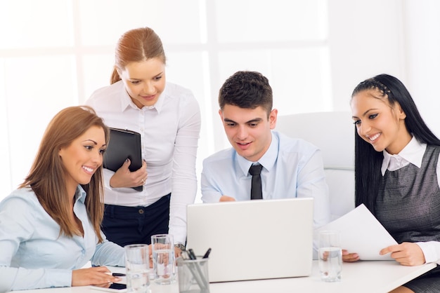 Exitosos jóvenes colegas sonrientes que trabajan en una laptop en la oficina.