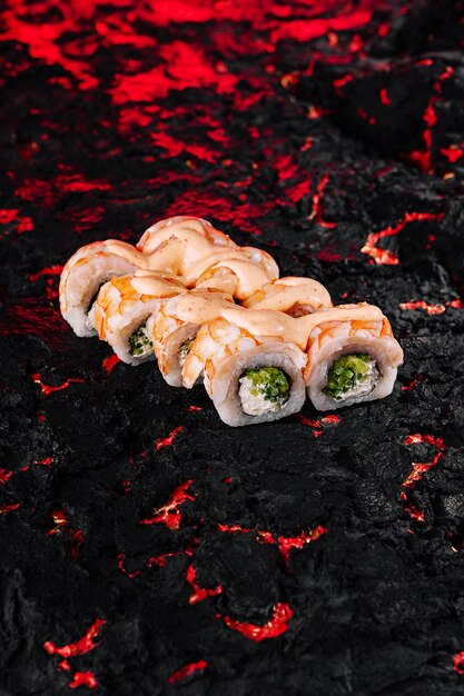 Foto exóticos rollos de sushi en una placa de lava con textura