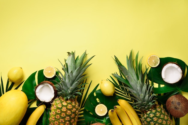 Exotische Ananas, reife Kokosnüsse, Bananen, Melonen, Zitronen, tropische Palmen und grüne Monsterblätter