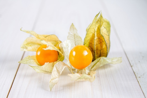 Exotische Beerenphysalis auf einem weißen Holztisch.