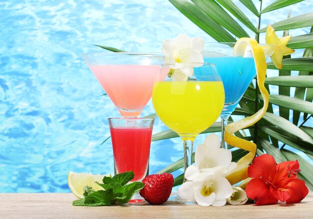 Exotische Cocktails und Blumen auf dem Tisch auf blauem Meeresgrund