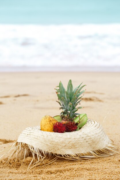 Exotische Früchte in einem Strohhut am Meer