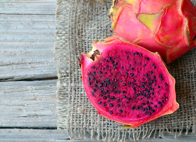 Exotische reife rosa Pitaya oder Drachenfrucht. Rote Pitahaya tropische Frucht halbiert auf altem Holztisch. Selektiver Fokus.