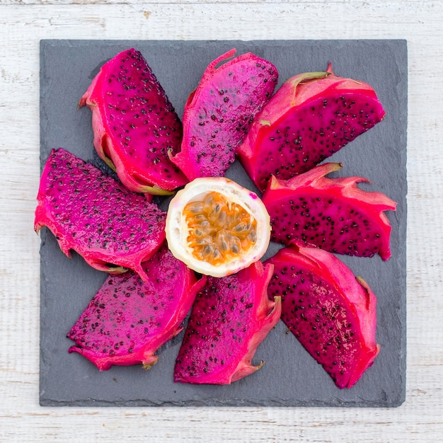 Exotische rosa Drachenfrucht geschnitten und Passionsfrucht auf dem Hintergrund in Nahaufnahme. Süße tropische Frucht, saftige Pitaya und Passionsfrucht geschnitten auf weißem Holztisch