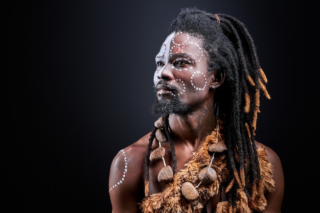 Exotischer Aborigen mit ethnischem Make-up im Gesicht, hemdloser Mann mit Dreadlocks