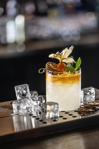 Exotisches Mai Tai-Cocktailgetränk, geschmückt mit Physalis und Minze, auf der Barbank des Pubs