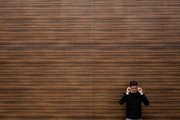 Experiência de conhecimento de sucesso carreira de finanças. homem de negócios confiante inteligente reorganizando os óculos. fundo de parede de textura de madeira. rua ao ar livre. conceito de copyspace