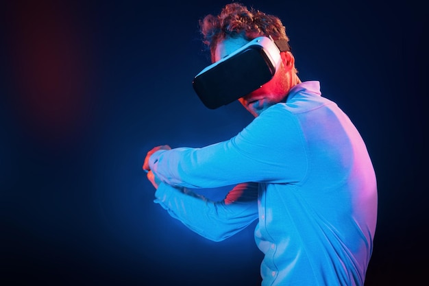 Experiencia de juego de gafas virtuales Iluminación de neón Joven europeo está en el estudio oscuro