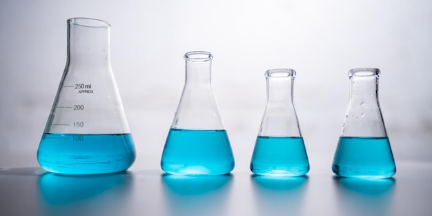 Experiment mit blauer chemischer Flüssigkeit in wissenschaftlichen Glasgeräten in der Wissenschaftsmedizin, Laborchemie oder Biologie, Forschungsentdeckung unter Verwendung von Glas aus Reagenzglas oder Becher und Kolben