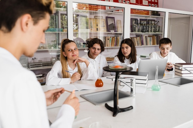 Experimento con fuego El profesor de química de la escuela muestra a los niños experimentos en el laboratorio Concepto educativo Lección grupal de compañeros de clase en la lección de química