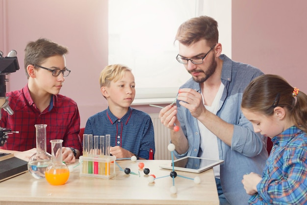 Experimentos físicos na escola, crianças construindo um modelo de átomo no local de trabalho do laboratório, copie o espaço. Educação de tronco. Desenvolvimento inicial, educação, diy, conceito de inovação.