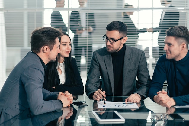 Experto analizando gráficos financieros en una reunión con el equipo empresarial