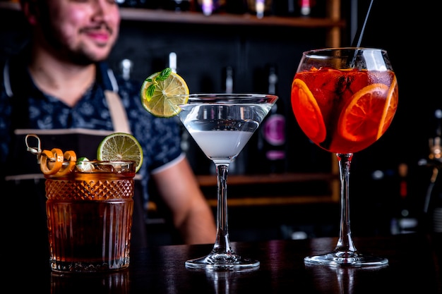 El experto barman está haciendo un cóctel en el club nocturno. Camarero profesional en el trabajo en el bar vertiendo una bebida dulce en un vaso en la fiesta en el club nocturno. Barman está decorando cócteles.