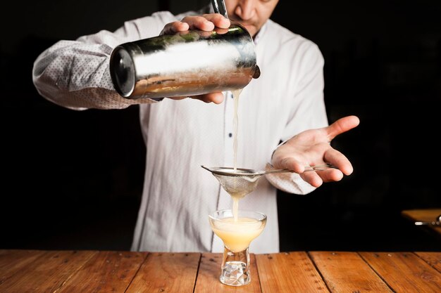 Experto barman haciendo un delicioso cóctel en una barra de madera