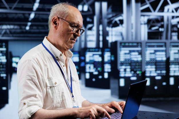 Experto con licencia que usa una computadora portátil, configura servidores de juegos multijugador dedicados de alto ancho de banda en la sala de supercomputadoras para acomodar más tráfico desde ubicaciones en todo el mundo y evitar retrasos obstructivos