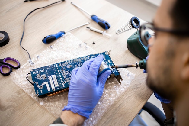 Un experto en reparación de dispositivos electrónicos y placa base de soldadura en servicio informático.