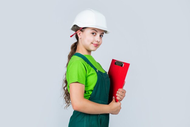 Experto en seguridad. niño use casco en el sitio de construcción. constructor de chica adolescente con documento de papel de construcción. niño en trabajos de reparación. concepto de renovación en taller. carpintero profesional ocupado.