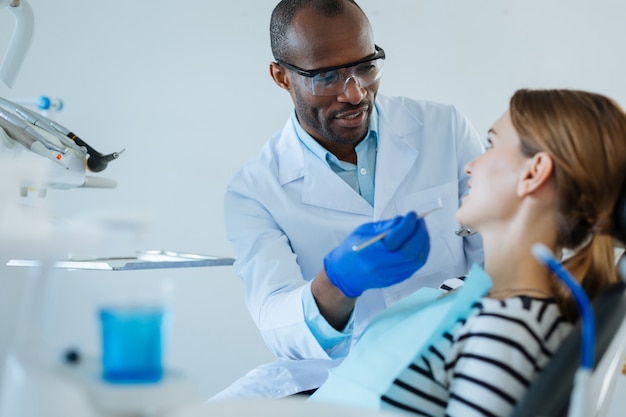 Explicación clara. Encantadora joven escuchando atentamente a su dentista masculino mientras él le explicaba el protocolo de tratamiento