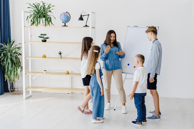 Explicando a lição e usando o quadro Grupo de alunos de crianças de diferentes idades em sala de aula na escola com o conceito de aprendizagem do professor